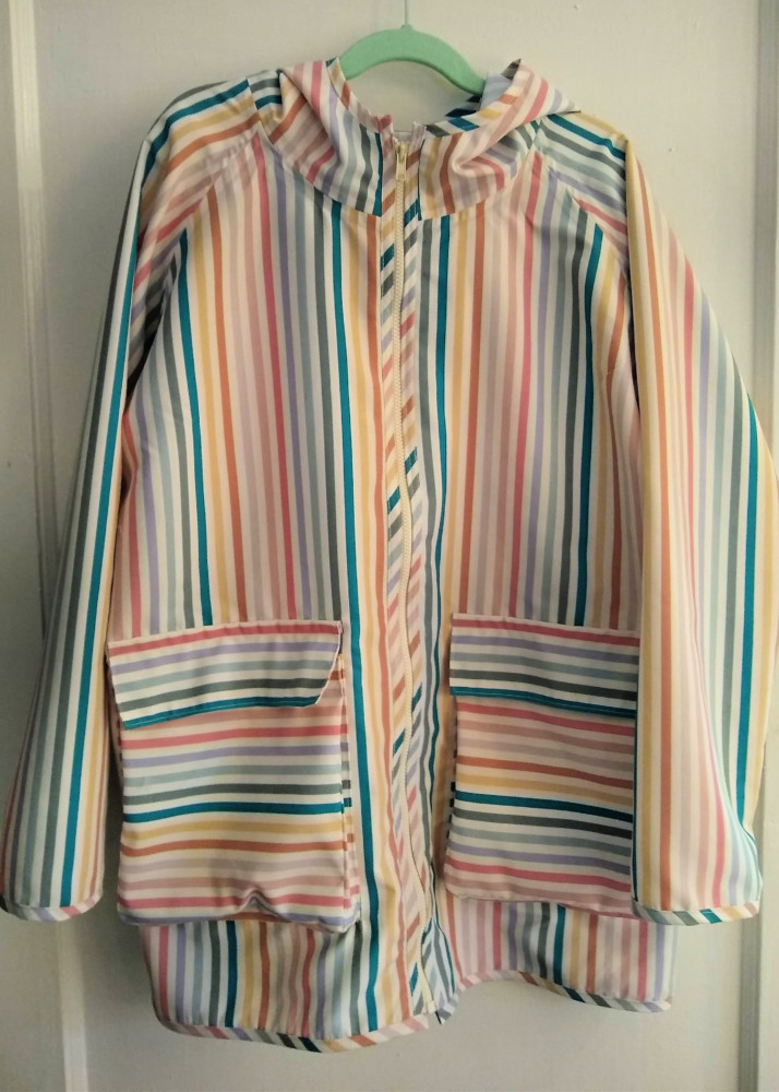 Striped raincoat made out of board short fabric hanging against a door
