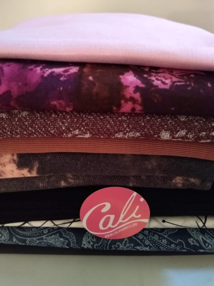 A stack of gorgeous fabrics with a sticker reading Cali Fabrics in front of them.